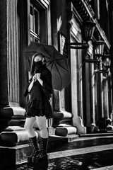 Woman in a black dress and a mask with an umbrella in her hands