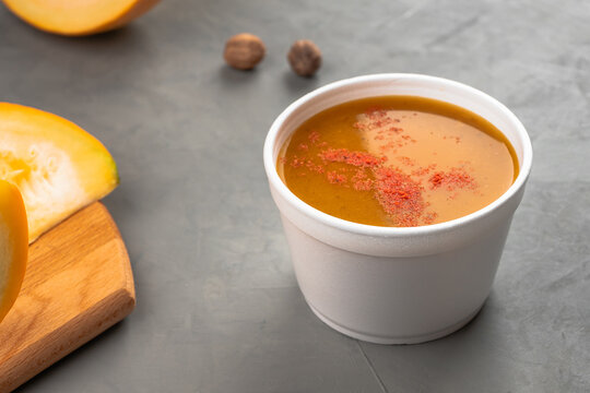 Pumpkin soup in a disposable soup plate near the pumpkin slices