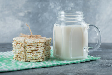 Delicious square crispbread and bottle of milk on marble background