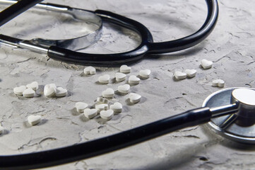 a stethoscope and heart-shaped pills. Concept of treatment of heart diseases