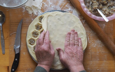 Making homemade dumplings with a special mold. An elderly woman is hands are busy preparing food.