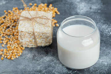 Stack of crispbread and glass of milk on marble background