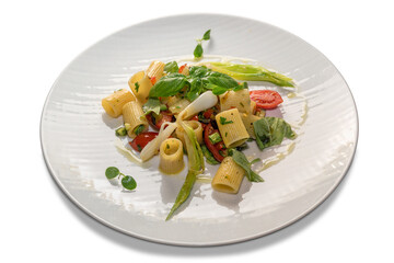 Half striped paccheri with tomatoes, basil and spring onion. Pasta macaroni italian cooked seasoned in white plate isolated on white background