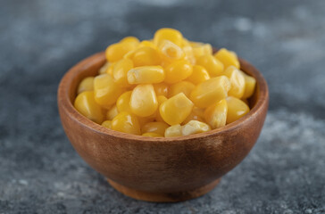 An wooden bowl of popcorn seeds on a marble background