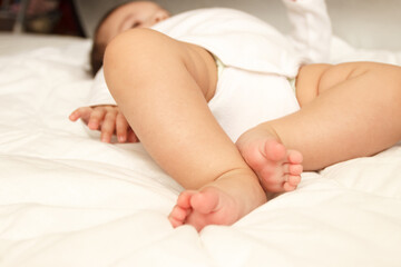 Obraz na płótnie Canvas Legs of infant on the white blanket, bedroom, blurred background