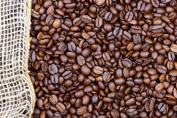 Background, close-up and texture of roasted coffee beans with a piece of jute running along the edge