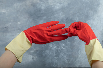 Hands wearing red protective gloves on marble background
