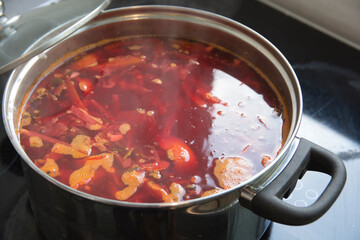 A boiling pot of traditional sour Borscht soup,  one of the most famous dishes of Ukrainian cuisine, made with beetroots as one of the main ingredients, which give the dish its distinctive red color