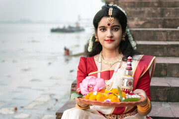 Portrait of beautiful Indian woman draped in traditional saree, adorned with gold jewellery,...