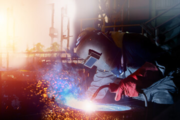 Industrial worker welding metal piping using Mig welder and wear equipment protection mask in shipyard,