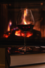 Glass of red wine in front of the fireplace.