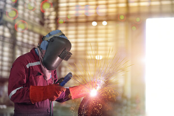 Industrial Worker at the factory welding process close up with protective equipment mask, PPE marks welder on bokeh background.