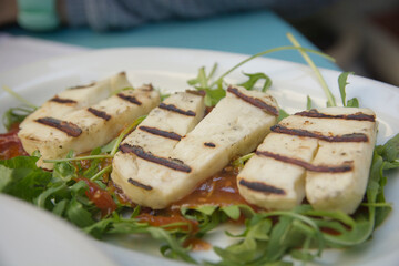 Three roasted slices of Greek Halloumi cheese, a semi-hard, unripened, brined cheese, made from a mixture of goat's and sheep's milk. Served in a plate with a salad, Thessaloniki, Greece