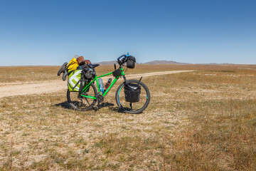 Fototapeta na wymiar Touring bike full loaded standing on a dirty road. tourist bike with bags. Mongolian steppe.