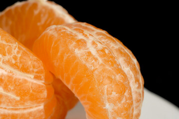 Juicy peeled mandarin against dark background closeup. Shallow depth of field