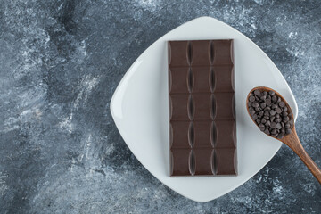 Bar of chocolate with chocolate chips on a marble background