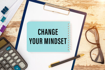 Notebook with text CHANGE YOUR MINDSET near office supplies.