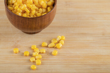 A wooden bowl of popcorn seeds on a wooden table