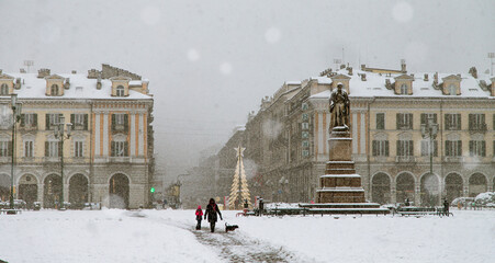 piazza cittadina con mamma, bimba e cane che passeggiano sotto una fitta nevicata