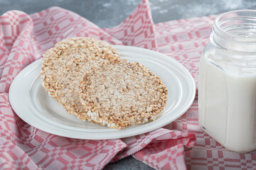 A white plate full of puffed rice bread with a jar of milk