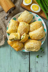 Ukrainian or Russian cuisine. Baked small pies with egg and green onions, spring vitamin baked goods. Top view flat lay. Copy space.