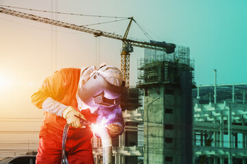 Construction worker welding Tig on Building construction site with structrue steel and tower crane...
