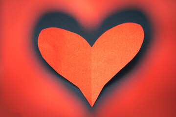 Red heart on a black background. The red paper heart is visible through the heart shape.