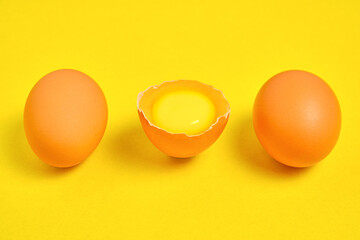 Chicken eggs on a yellow background broken with yolk.