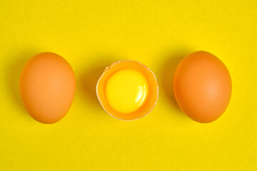 Chicken eggs on a yellow background broken with yolk.