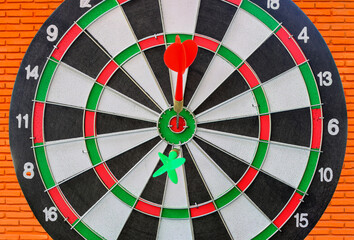 close up Dart hitting on Dartboard on brick wall background.