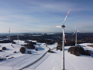 Aerial view of a wind farm in a winter landscape during sunset. Aerial view of wind turbines during sunset.