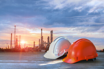 White and Orange hard hat Safety helmet stacked Oil Refinery factory Sunrise in background The concept of safety cooperation in refineries.
