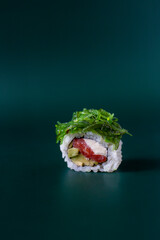 Roll with tuna and chuka seaweed on a dark green background, top view