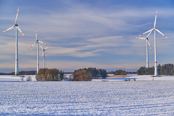 Windfarm on snowy farmland during sunset. Wind turbines on snowy farmland during sunset.