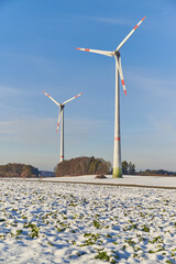 Windfarm on snowy farmland during sunset. Wind turbines on snowy farmland during sunset.