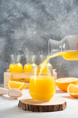 A glass bottle pouring orange juice on a wooden board