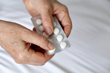Elderly woman with pills in wrinkled hands. Concept of medication for heart, sedatives