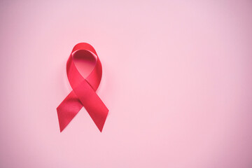 World cancer day and breast cancer day concept, Red ribbon awareness symbol on pink background. Cancer is cause of number one human die in the world due to behavior lifestyle , food and heredity.