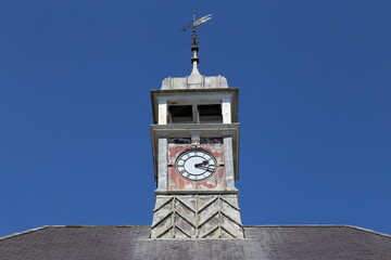 A close up view of the dilapidated clock tower with weather vane on a Town Hall building in Wales.