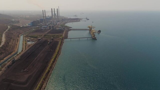 power station with spillway by sea with smoking pipes, paiton java, indonesia. aerial view power plant in asia.