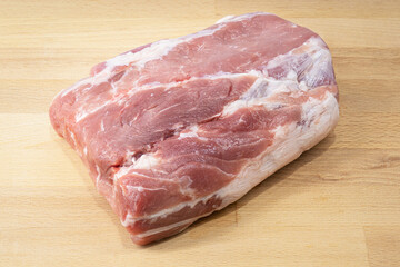 A big piece of raw red pork meat on wooden cutting board, preparing for make a steak. Food close-up photo. 