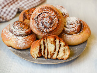 fresh homemade yeast dough buns with cinnamon and powdered sugar on white wooden background