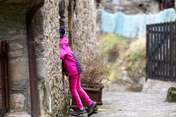 Niña mirando por una ventana de una casa de piedra en Beget, Pirineo, Cataluña, España