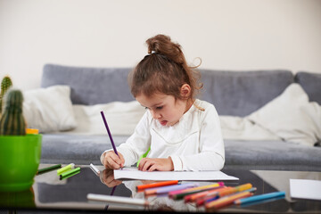 Beautiful preschool girl focused on drawing. Concept of preschool education at home.