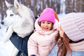 mixed race family in threesome spending new year holidays in park with their husky dog