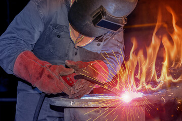 Welding Worker by hand holding MIG with spark light in factory on flame background jpt and hard...