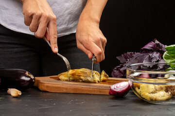 Cooking process, woman cut baked eggplant