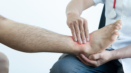 The doctor is examining a patient whose ankle is injured. The man was injured during a home...