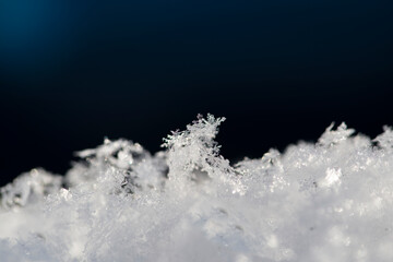 Abstract dark blue-white natural background. Snowflakes on a dark background close-up. Selective focus