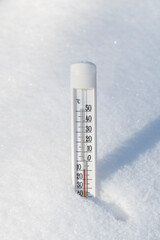 A thermometer in a snowdrift in winter shows a low temperature. Weather concept.
